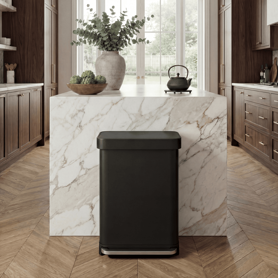 Simplehuman's 55L Step Can in Matte Black in a modern luxury home setting with marble countertops and wooden cabinets.